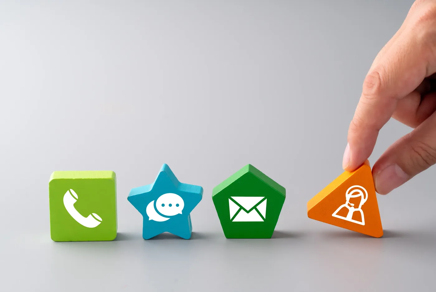 Coloured wooden shapes carrying phone, message, email and support symbols, representing different ways to make contact.