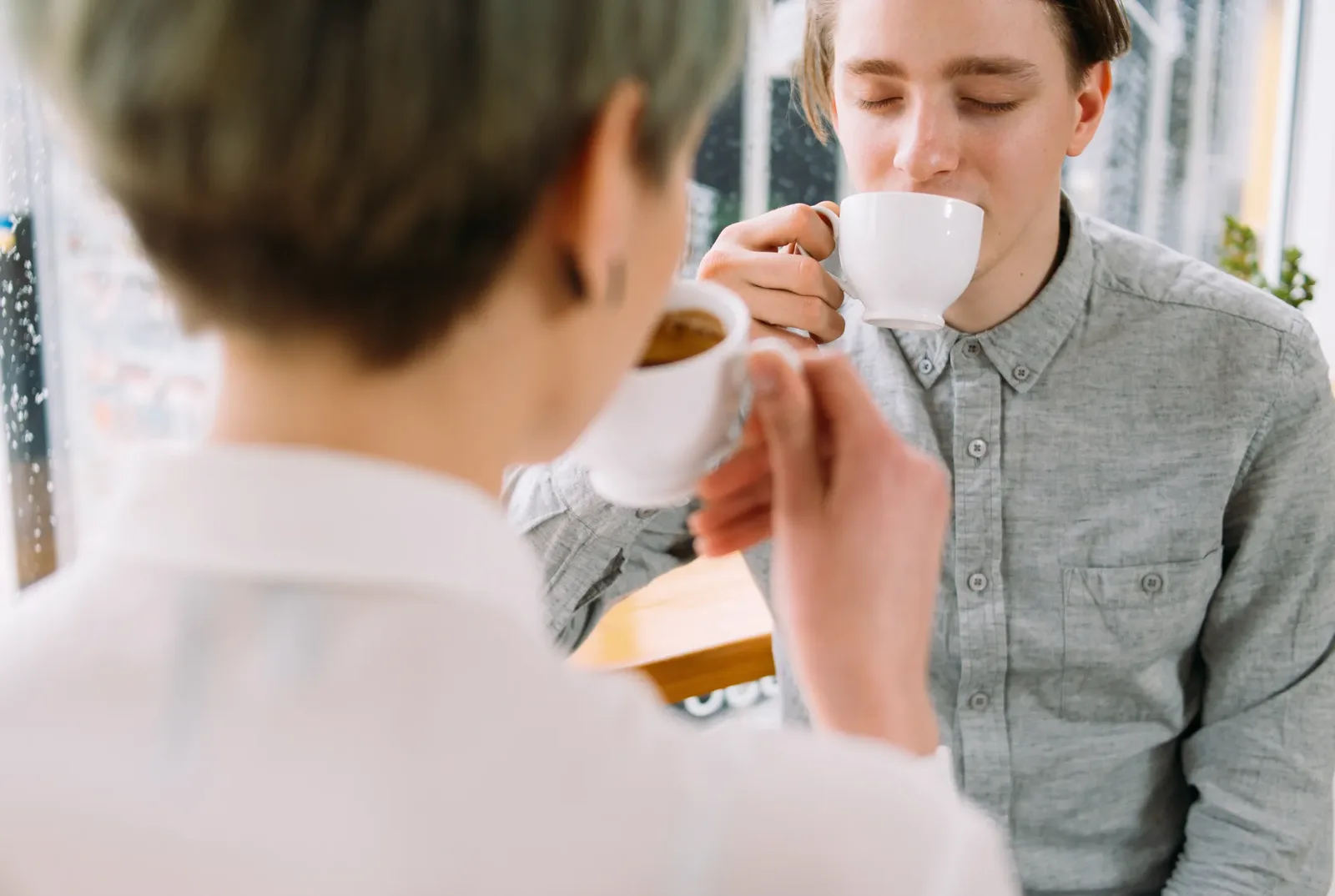 Two people sitting together with cups of coffee in a bright room, illustrating how caffeine often forms part of a social ritual.