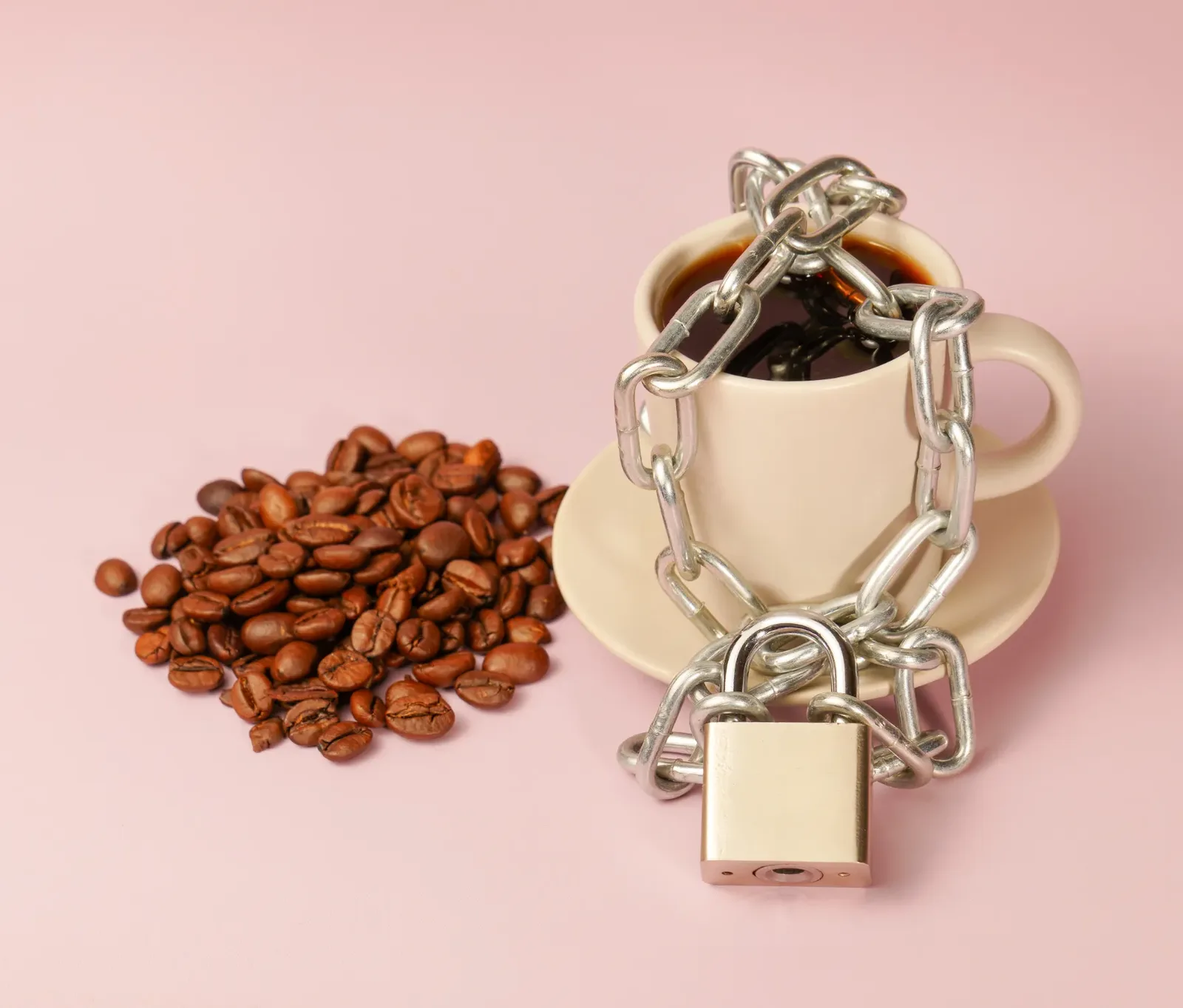 A cup of black coffee beside a scattering of roasted coffee beans, representing everyday caffeine sources.